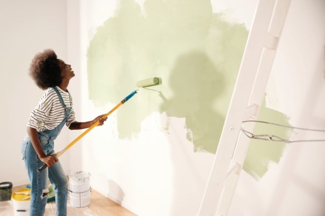 An image of a person painting a white wall green. 