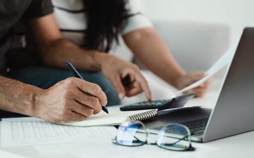 Two people sit on a couch and manage their finances.