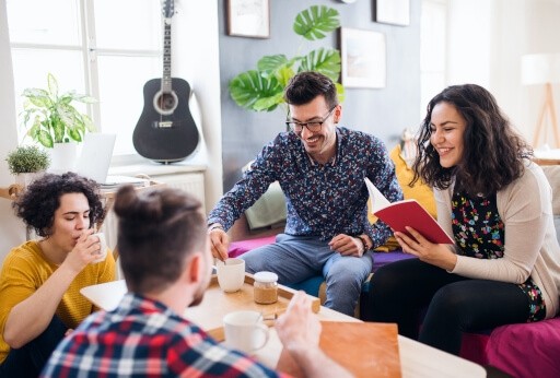 Group of students chatting and drinking coffee on the couch in their apartment.