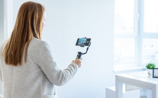 Woman recording apartment with phone.
