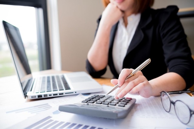 Woman using a calculator and a laptop