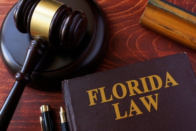 A wooden desk with a Florida law book on top and a gavel.