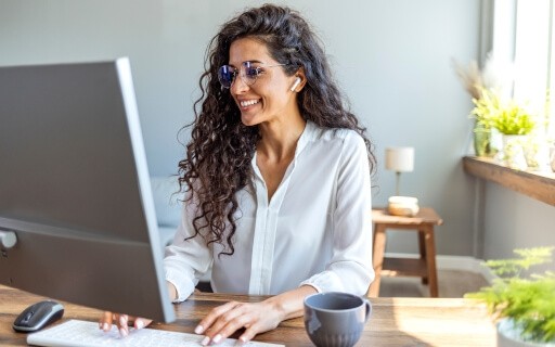 Woman smiling and typing on computer.