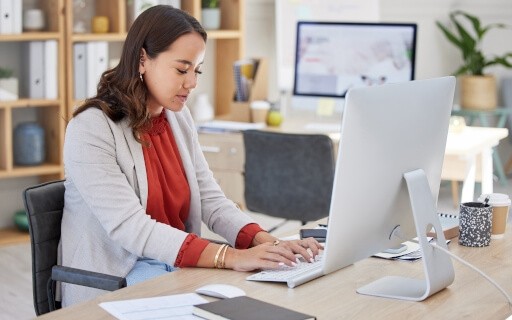 Woman typing on computer in office.