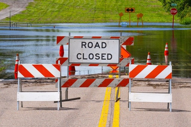 A flooded street with a road closed sign