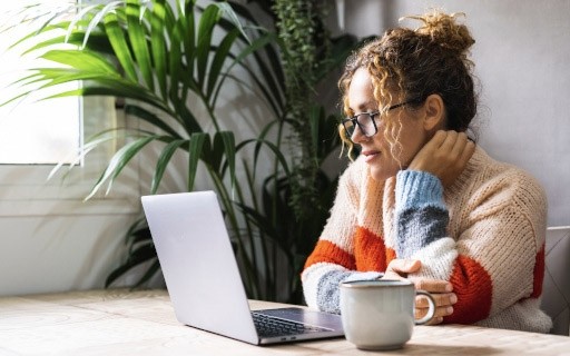 A woman looks at something on a laptop.