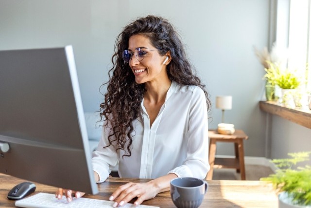 Person typing on computer keyboard and smiling
