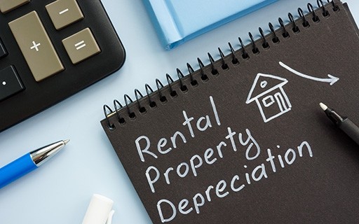 The words "rental property depreciation" written on a notebook.