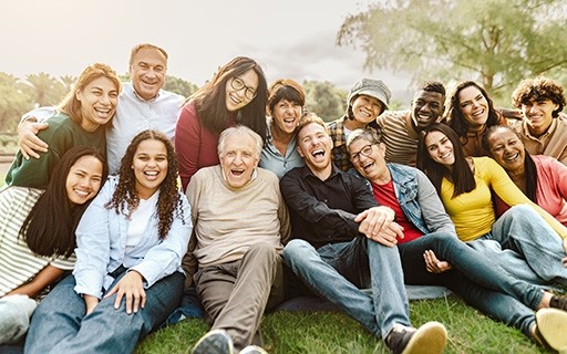A group of people of all ages sitting outside and smiling.