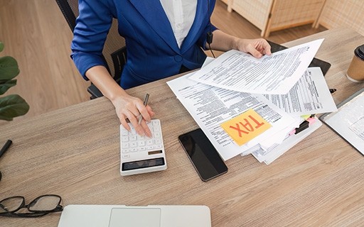 A professional woman using a calculator as she files taxes.