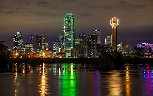 The skyline of Dallas over the water lights up at night.