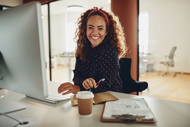 Lady sitting at desk using a computer and smiling