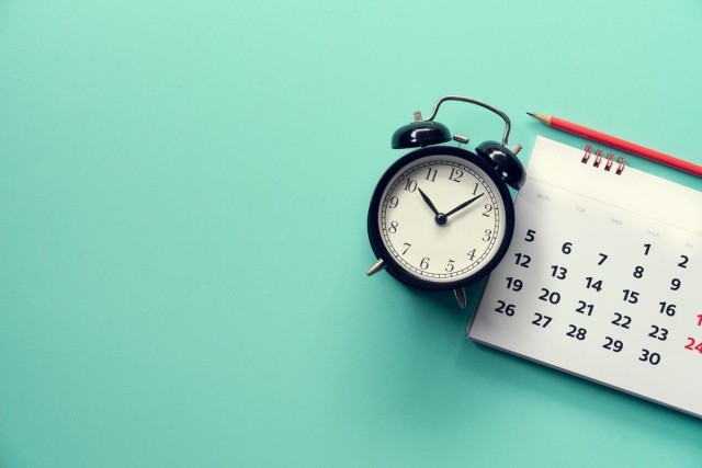 A plain background with an old-fashioned clock, a calendar, and a pencil