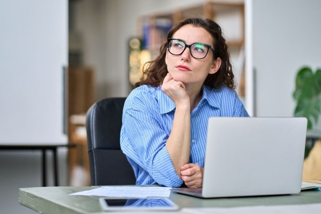 A lady sitting at her desk with a deep thinking expression