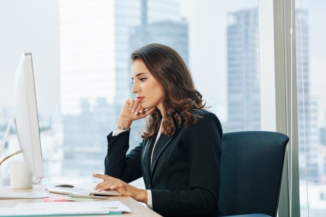 Businesswoman staring at her computer trying to make a decision