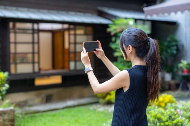 A lady taking a picture of the front of a home