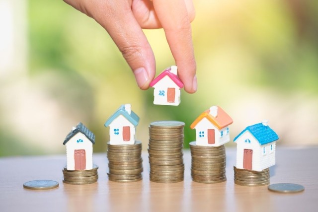 Miniature houses sitting on stacks of coins at different levels