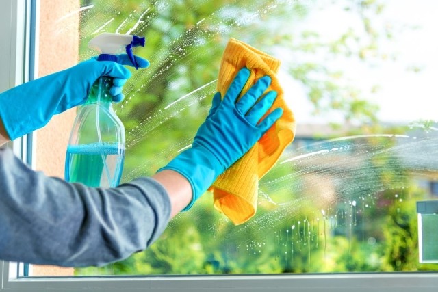 Person cleaning windows with a spray bottle and cloth