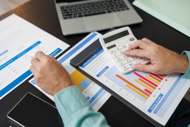 A person looking at charts and a calculator