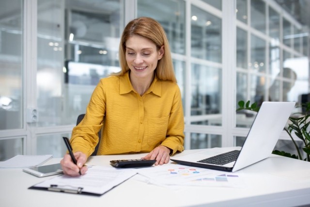 Woman writing with pen and using a calculator