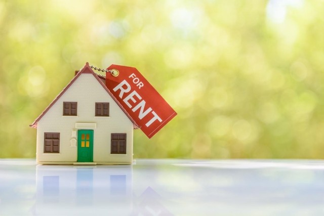 A tiny model house sitting on a table with a key chain on top