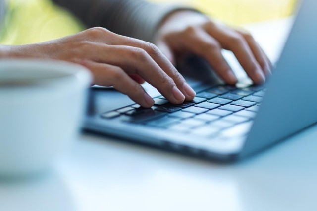 Two hands typing on a laptop