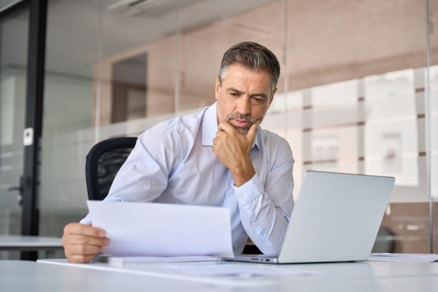 Man sitting in front of laptop reviewing a document
