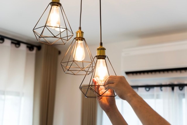 A person changing lightbulbs on a modern light fixture