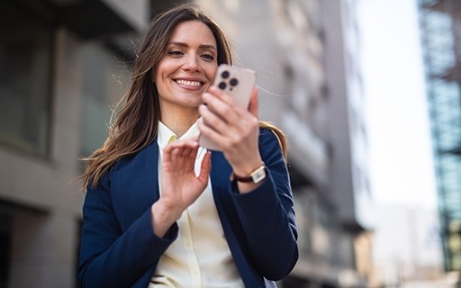 A landlord in a blue suit smiles at her smartphone.
